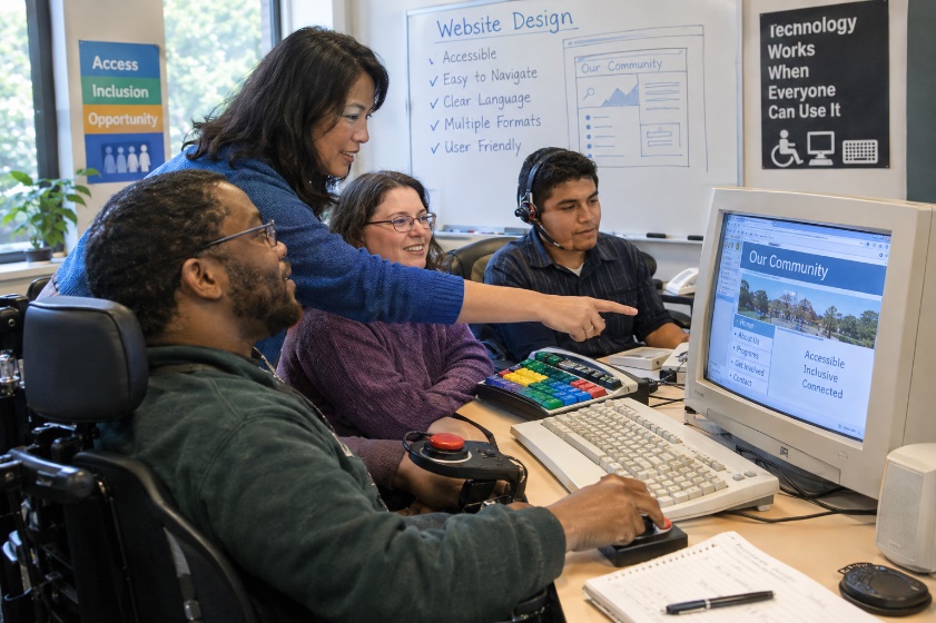 A C4AT staff member assists people with disabilities during a website design workshop.