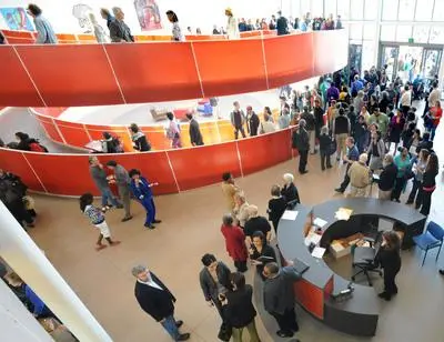 People gather around the red spiral ramp inside the Ed Roberts Campus.